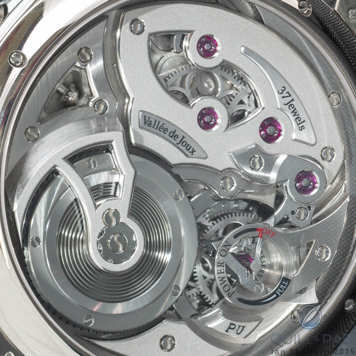 The partial sapphire mainspring barrel for lower friction (more constant force) visible bottom left through the display back of the Roman Gauthier Logical One Secret Kakau Höfke. The power reserve indicator is at the lower right